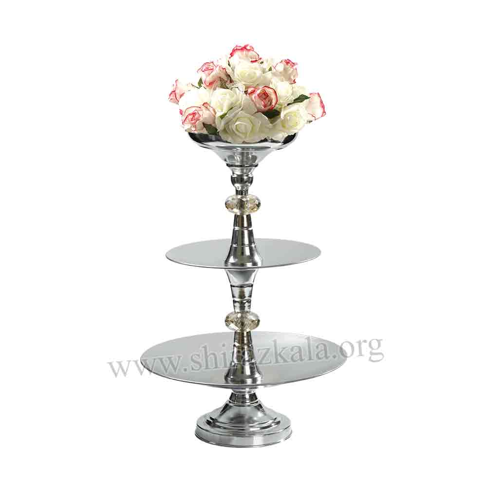 تصویر  ظرف سه طبقه نقره‌ای میوه و شیرینی با گل مصنوعی پیونی